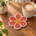 Petal Pop crochet coaster in pink and cream flower shape beside a latte mug