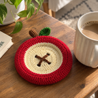Apple Slice crochet coaster with cream center and red border beside a mug