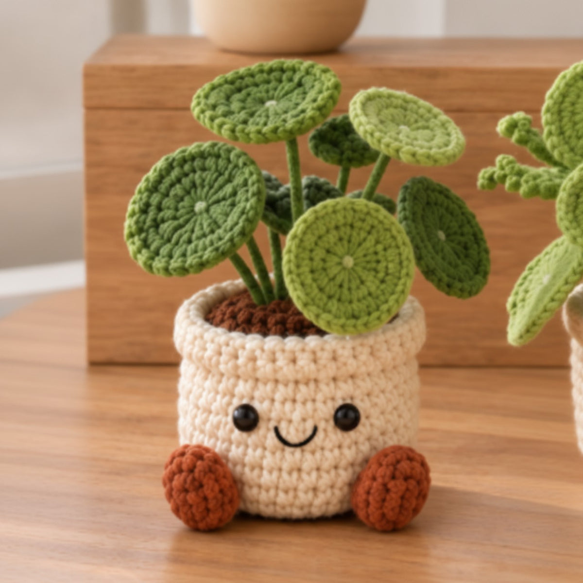 Pilea crochet plant decor with round green leaves in a smiling cream pot