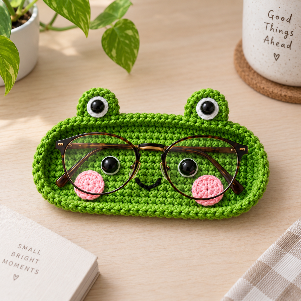 Happy Frog crochet glasses holder in bright green with raised eyes, rosy cheeks, and eyeglasses