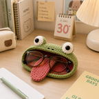 Funny Frog Tongue crochet glasses holder with eyeglasses displayed on a desk with books, lamp, and stationery