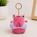 Pink frog crochet keychain with lavender outfit detail and large playful eyes