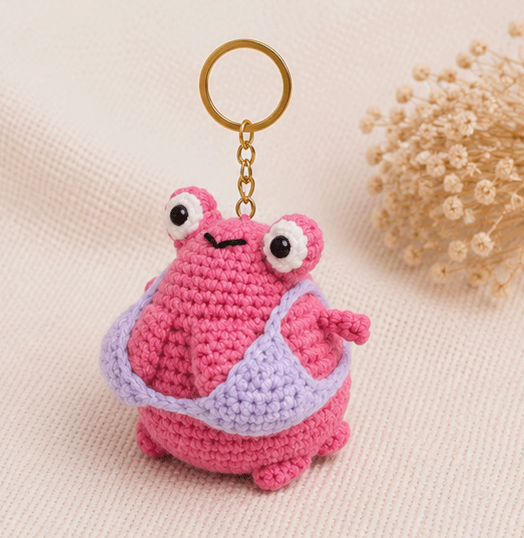 Handmade pink frog crochet keychain shown from a front three-quarter angle