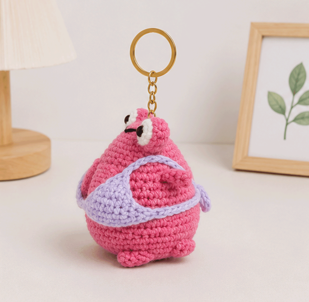 Side view of pink frog crochet keychain with lavender crochet detail